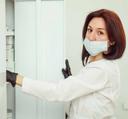 женщина врач достаёт из шкафа необходимые препараты для процедуры УБОД